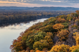 A river and bluff with trees turning colors.