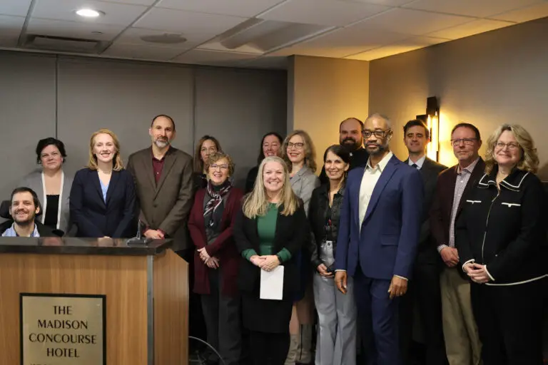 A group of advocates around the lectern at a press conference related to FoodShare funding. LOPPW is represented by Kacy Kostiuk and Pastor Andy Twiton.